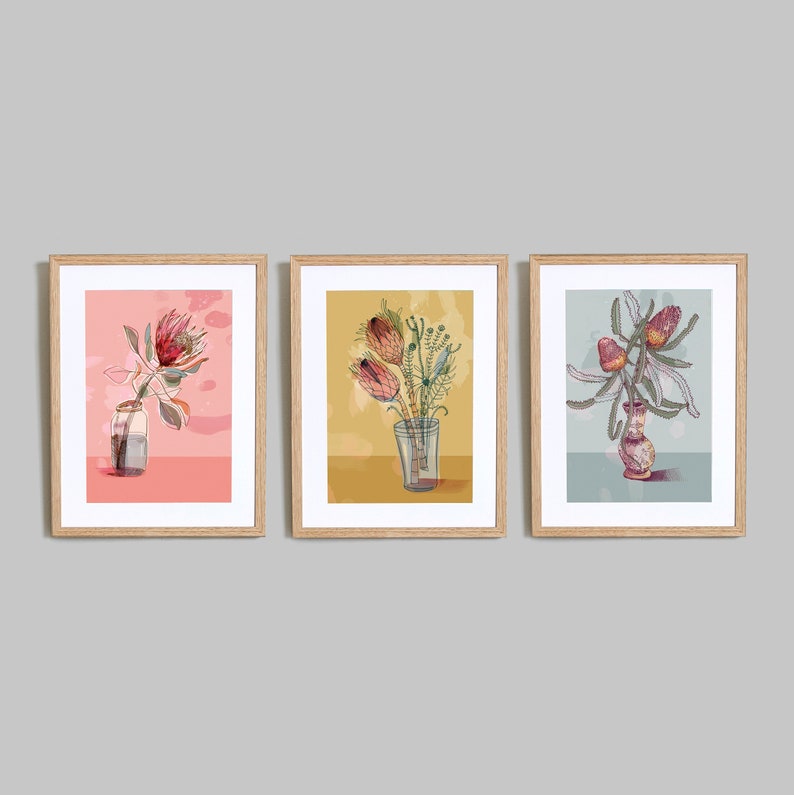 May include: Three framed prints of botanical illustrations featuring pink, red, and yellow flowers in glass vases. The prints are set against a light pink, yellow, and blue background.