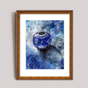 Puede incluir: Un jarrón de porcelana azul y blanco con diseños florales se encuentra sobre un fondo con estampado azul y blanco. El jarrón está en un marco marrón.