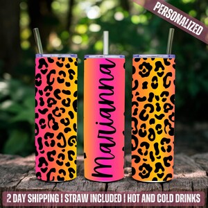 May include: Three stainless steel tumblers with a leopard print design. The tumblers are in a gradient of pink, orange, and yellow. The middle tumbler has the name "Marianna" written on it in black.