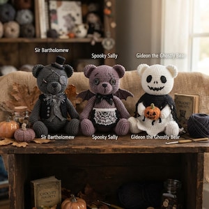 Op de afbeelding: Drie gehaakte knuffelberen genaamd Sir Bartholomew, Spooky Sally en Gideon the Ghostly Bear. Sir Bartholomew is donkergrijs met een hoge hoed en vest. Spooky Sally is paars met vleermuisvleugels en een spinnenweb-schort. Gideon is wit en houdt een pompoen vast.