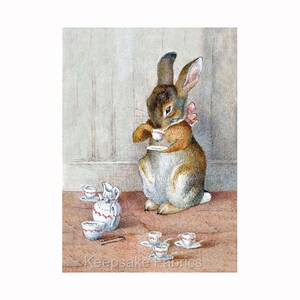 May include: A brown rabbit wearing a pink bow sits at a table with a tea set. The rabbit is holding a small teacup and saucer. There are several other teacups and saucers on the table, as well as a small teapot.