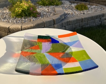 May include: A colorful glass serving dish with a geometric pattern in shades of red, green, blue, and white.