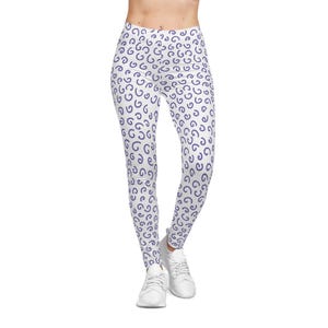 May include: White leggings with a repeating pattern of navy blue curved shapes. The leggings are high-waisted and worn with white sneakers. The overall look is casual and sporty.