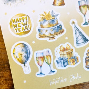 May include: Sheet of New Year's Eve stickers featuring watercolor illustrations. Designs include fireworks, balloons, party hats, champagne glasses, a two-tiered cake, and gift boxes. The text "HAPPY NEW YEAR!" is also included.