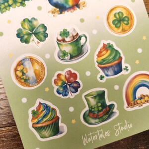 May include: A sheet of stickers with St. Patrick's Day themed designs. The stickers include a rainbow, a pot of gold, shamrocks, cupcakes, a green top hat, and a cup of hot chocolate. The stickers are on a light green background.
