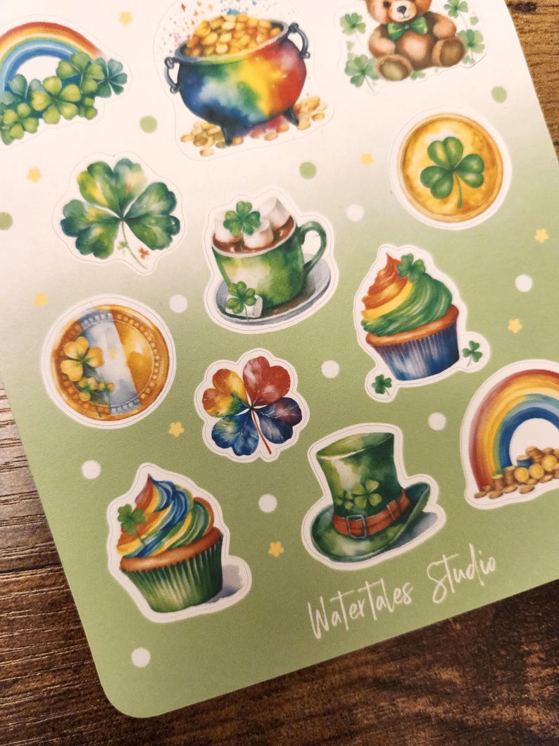 May include: A sheet of stickers with St. Patrick's Day themed designs. The stickers include a rainbow, a pot of gold, shamrocks, cupcakes, a green top hat, and a cup of hot chocolate. The stickers are on a light green background.