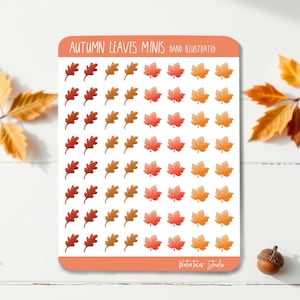 May include: A sheet of autumn-themed stickers featuring hand-illustrated leaves in shades of red, orange, and brown. The sticker sheet has the text "Autumn Leaves Minis" and "Hand Illustrated". The stickers are arranged on a white background.