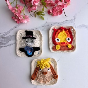 May include: Three crocheted squares featuring characters from a popular animated film. One square depicts a scarecrow with a black hat, another a fiery creature, and the last a light brown bunny with yellow hair. The squares are cream-colored with detailed stitching.