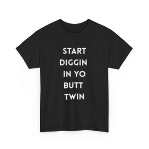 May include: Black t-shirt with the white text "START DIGGIN IN YO BUTT TWIN" vertically aligned. The shirt is a crew neck style and appears to be made of a soft material.