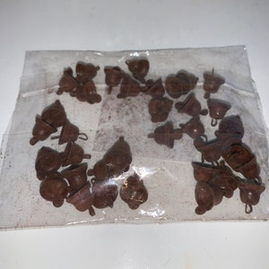 May include: A bag of brown metal bells with a loop on top. The bells are in a clear plastic bag.