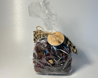 May include: A clear cellophane bag filled with dark red items, tied with a black and yellow plaid ribbon and twine. A small, round tag with the words "Snicker Doodle" is attached to the bag.