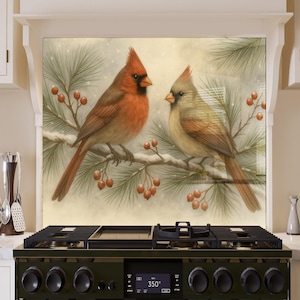 Puede incluir: Panel decorativo para cocina con dos cardenales posados en una rama nevada con bayas rojas. El cardenal macho es de color rojo brillante, mientras que la hembra es de color marrón apagado. El fondo es una escena invernal suave y borrosa.
