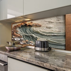 May include: A kitchen countertop with a brown and grey marble pattern. A black toaster is on the counter, and a copper frying pan is on the hob. A framed artwork of a wave crashing against a rocky shore is on the wall behind the counter.