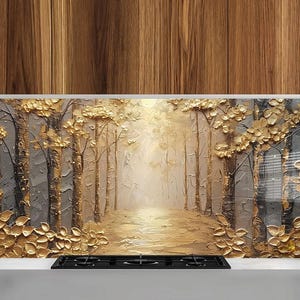 Può includere: Un paraschizzi da cucina dorato e grigio con un design dipinto di una foresta con alberi e foglie. Il paraschizzi è installato sopra un fornello a gas nero.