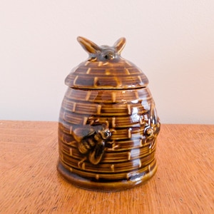 Vintage bruine honingpot bijenkorfvorm bij bovenop kleinere bijen rond de pot bruine honingpot met bijendeksel