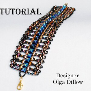 Könnte beinhalten: Ein Armband aus Perlen mit einem geometrischen Muster in Schwarz-, Blau-, Gold- und irisierenden Lilatönen. Das Armband hat einen Karabinerverschluss. "TUTORIAL" und "Designer Olga Dillow" sind im Bild zu sehen.