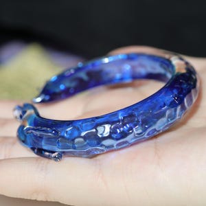 May include: A blue glass bangle bracelet with a textured surface.