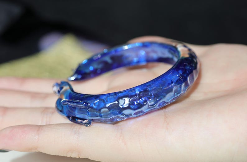 May include: A blue glass bangle bracelet with a textured surface.