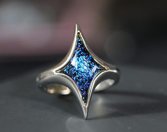 May include: A silver ring with a blue, star-shaped glass stone.