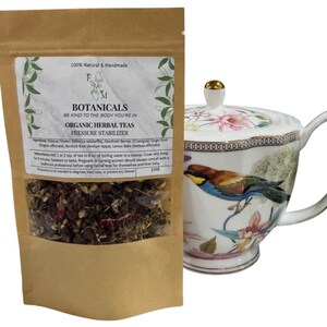 May include: A brown paper pouch with a white label that reads "Botanicals, Be Kind to the Body You're In, Organic Herbal Teas, Pressure Stabilizer". The pouch contains a blend of dried herbs. The pouch is next to a white porcelain teapot with a floral design and a gold lid.