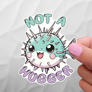 May include: A sticker with a cartoon pufferfish with the text "Not a Hugger" in purple lettering.
