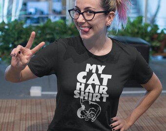 May include: Black t-shirt with the text "MY CAT HAIR SHIRT" in white block letters and a white graphic of a sleeping cat. The shirt is a crew neck style.