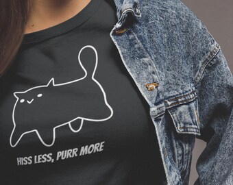 May include: Black t-shirt with a white outline of a cat and the text "HISS LESS, PURR MORE". The shirt is worn with a blue denim jacket.