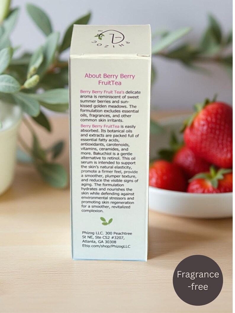 May include: A white box of Berry Berry FruitTea serum with text describing the product's benefits. The box is next to a bowl of fresh strawberries and a sprig of greenery. The label says "Fragrance-free".