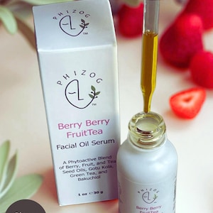May include: A white bottle and box of Berry Berry FruitTea Facial Oil Serum. The bottle has a dropper filled with yellow oil. The box and bottle have the brand name and product information. The image also includes strawberries.