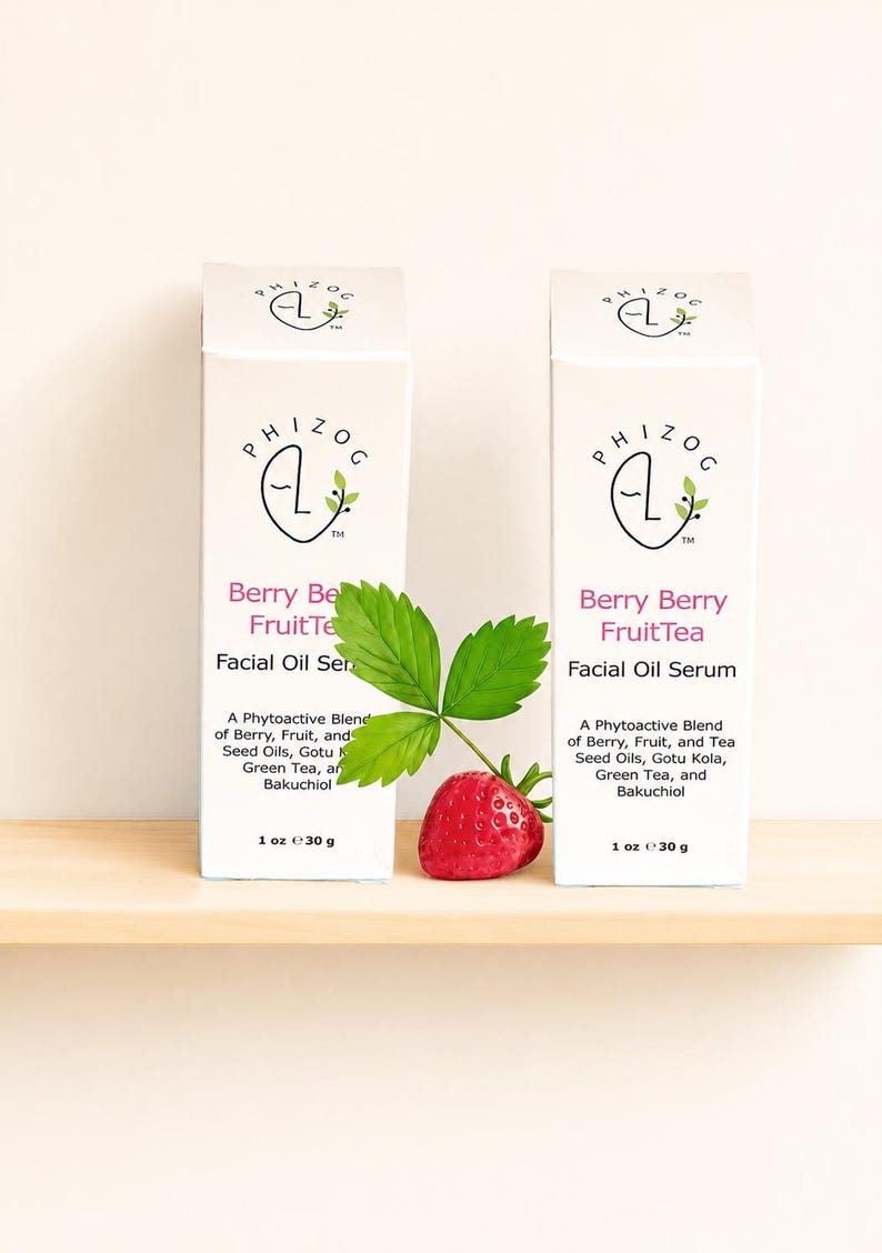 May include: Two white boxes of facial oil serum with the text "Berry Berry FruitTea" and "Facial Oil Serum". A strawberry and green leaf are in front of the boxes. Each box contains 1 oz of product.