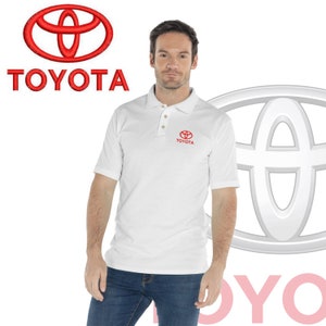 May include: A white polo shirt with a red Toyota logo embroidered on the left chest. The logo features the Toyota wordmark and the iconic Toyota emblem.
