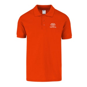 May include: Orange polo shirt with a white Toyota logo and the word "TOYOTA" embroidered on the right chest.