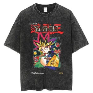 Pode incluir: Uma camiseta preta com um visual desbotado e desgastado. A frente da camiseta apresenta um gráfico do personagem de anime Yugi Moto da série Yu-Gi-Oh! O gráfico inclui o texto "Yu-Gi-Oh!" e "3-em-1 Volumes 1-2-3".