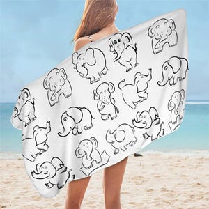 Puede incluir: Toalla de playa blanca con un contorno negro de elefantes en varias poses. La toalla está doblada y drapeada sobre los hombros de una persona.