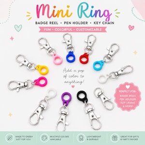 Op de afbeelding: Een collectie mini-ringbevestigingen voor badgehouders, penhouders en sleutelhangers, voorzien van zilverkleurige metalen karabijnsluitingen verbonden met kleine, ronde siliconen ringen in diverse kleuren, waaronder roze, blauw, rood, geel, wit, paars en zwart.