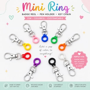 May include: A collection of nine mini ring attachments featuring silver-toned metal lobster clasps connected to small, solid-coloured silicone rings in pink, blue, green, orange, red, purple, black, and white, arranged in a circular pattern.