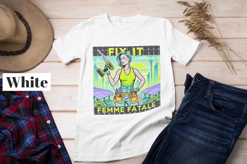 May include: White t-shirt with a graphic print of a woman holding a drill and wearing a tool belt. The graphic text reads 'Fix It Femme Fatale'.