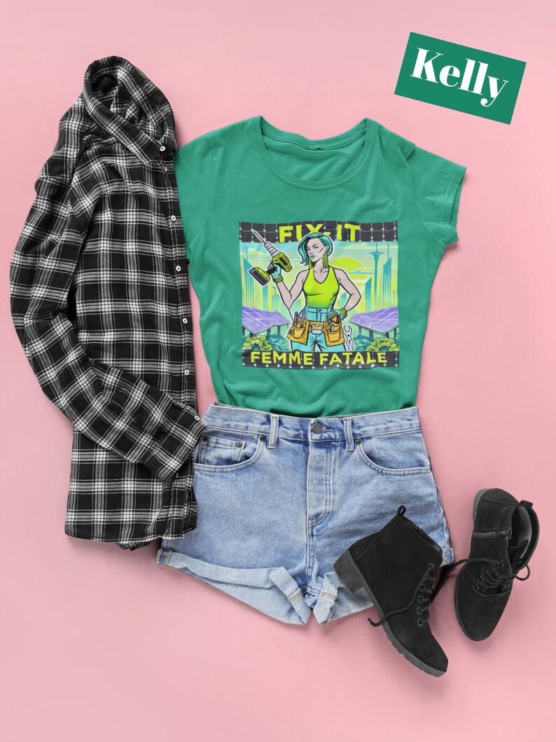 May include: A green t-shirt with a graphic of a woman holding a drill, the text "FIX IT FEMME FATALE". The shirt is styled with denim shorts, black boots, and a black and white checked shirt. A green rectangle with the name "Kelly" is in the top right corner.