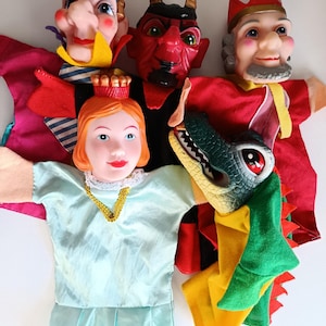 Puede incluir: Una colección de marionetas de mano vintage con varios personajes. Las marionetas incluyen un diablo con cuernos, un rey con corona, una princesa y un dragón. Las marionetas están hechas de tela y plástico, con colores vibrantes y rasgos faciales detallados.