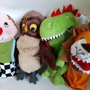 May include: A collection of plush hand puppets featuring a clown, owl, dinosaur, and lion. The clown has a red nose and a green outfit. The owl is brown with large yellow eyes. The dinosaur is green with red spikes. The lion has an orange mane.