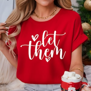 May include: Red t-shirt with white text that says "Let them" with two small hearts on either side of the text.