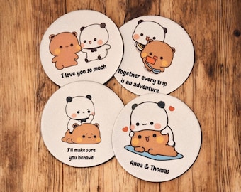 May include: Set of four round coasters with cartoon panda bear illustrations. Each coaster features a different design with phrases like "I love you so much" and "Together every trip is an adventure". The coasters are on a wooden surface.