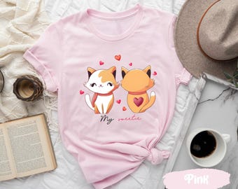 May include: Pink t-shirt with a graphic of two cartoon cats with hearts and the text "My sweetie".