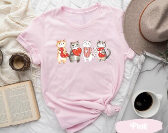 May include: Pink t-shirt with a graphic of four cats holding hearts that spell out "LOVE".