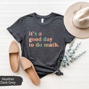 Puede incluir: Camiseta gris oscuro jaspeada con el texto "it's a good day to do math." en colores arcoíris.