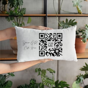 May include: White pillow with a black and white QR code that says "Scan Me" and the text "Your QR Code Here".