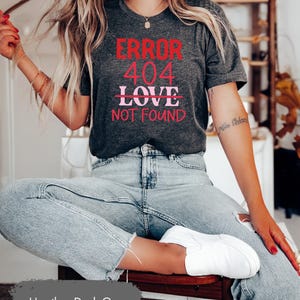 May include: Heather dark grey t-shirt with the text "ERROR 404 LOVE NOT FOUND" in red and pink lettering.