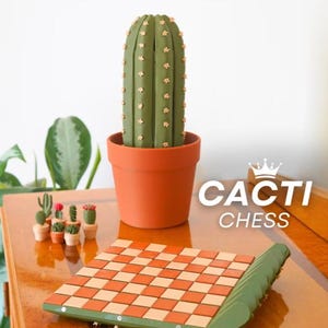 K&ouml;nnte beinhalten: Ein Schachspiel mit Kaktus-Motiv, mit einem gr&uuml;n-orangen Schachbrett und einer gro&szlig;en Kaktusfigur in einem Terrakotta-Topf. Das Set enth&auml;lt Miniatur-Kaktusfiguren und den Text "CACTI CHESS".