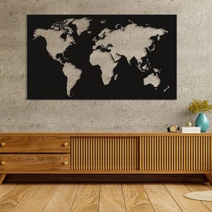May include: A black and beige world map wall art. The continents are beige against a black background. The artwork is mounted on a concrete wall above a wooden cabinet.