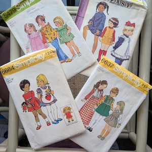Op de afbeelding: Vier vintage Simplicity naaipatroon enveloppen met illustraties van kinderkleding en schorten. De enveloppen tonen tekst zoals "Make it EASY, please" en prijskaartjes. De patronen zijn voor kindermaten.